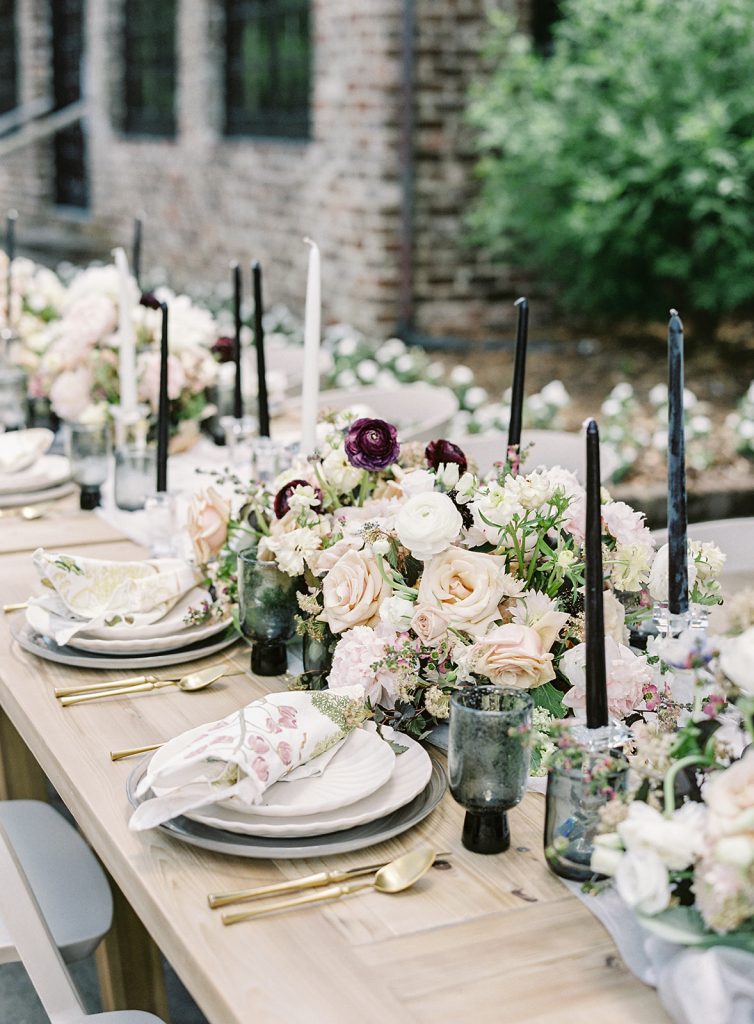 Ooh! Events designed outside reception table. White plates, gold flatware, black glassware and black and white candles and flowers going down the middle of the table and the full length of the king's table.  Photographed by wedding photographers in Charleston Amy Mulder Photography