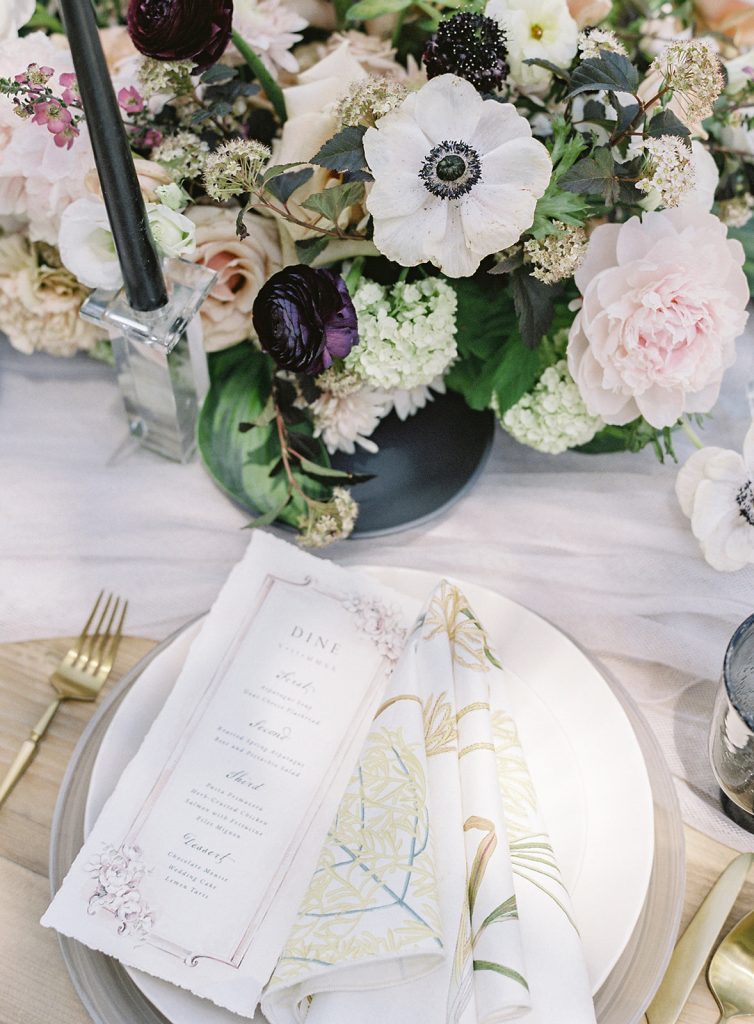 Ooh! Events designed outside reception table. White plates, gold flatware, black glassware and black and white candles and flowers going down the middle of the table and the full length of the king's table. With custom hand painted menu card on top. Photographed by wedding photographers in Charleston Amy Mulder Photography