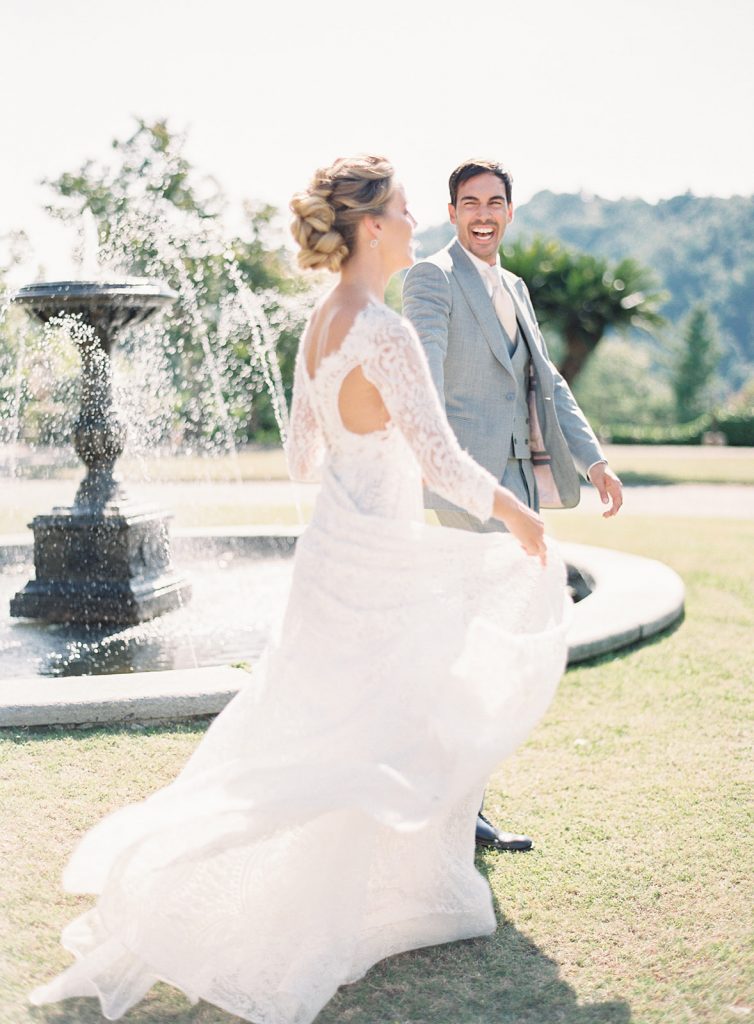 Couple holding hands and walking while looking at each other and laughing. He is facing the camera so you can see his big smile and joy as he is looking at her. Photographed at destination wedding in Italy by wedding photographers in Charleston Amy Mulder Photography.