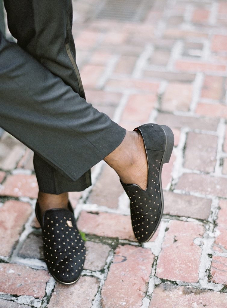 Groom's feet in black velvet shoes with gold detailing and no socks. Photographed by wedding photographers in Charleston Amy Mulder Photography.