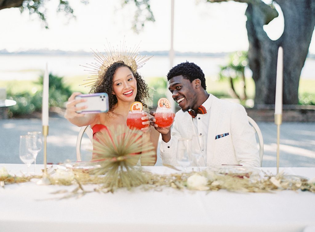 Couple at reception with red cocktails taking a selfie. Photographed by wedding photographers in Charleston Amy Mulder Photography