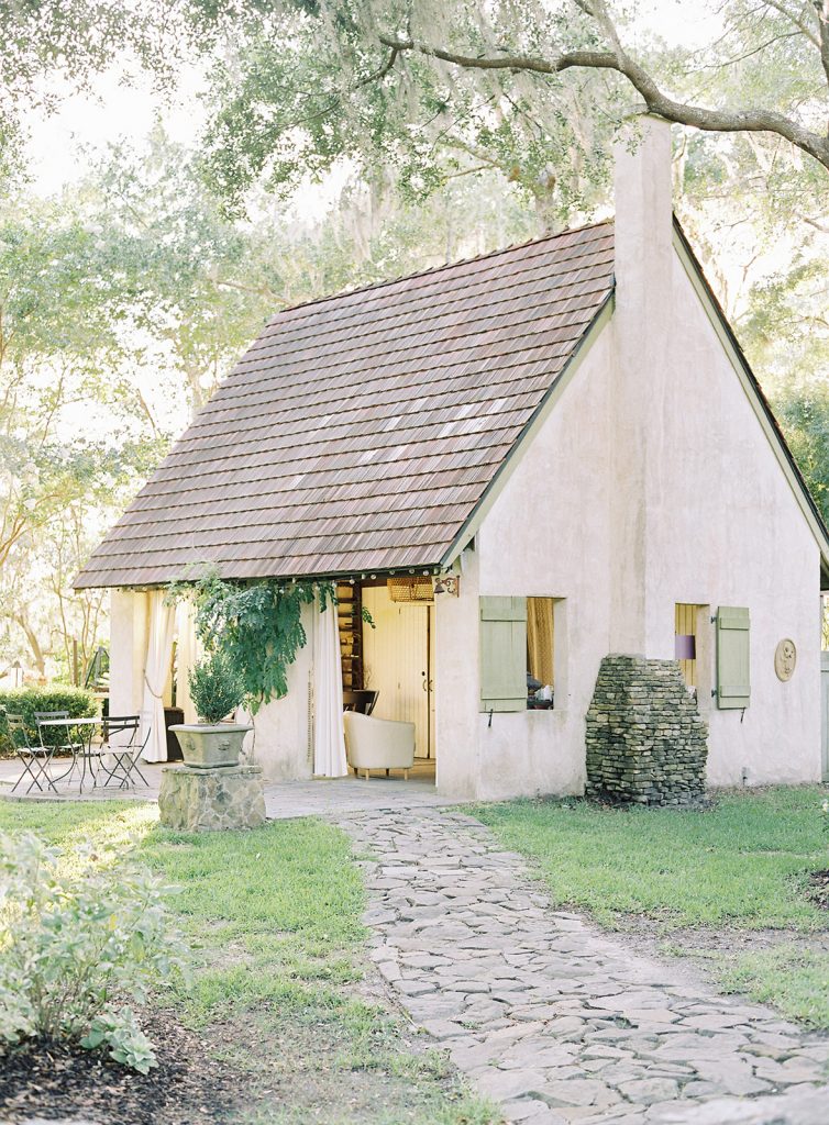 River Oaks Charleston wedding venue. Italian styled house cream colored with pastel green shutters. Stone path leading up to the house and large oak trees all around. Photographed by wedding photographers in Charleston Amy Mulder Photography.