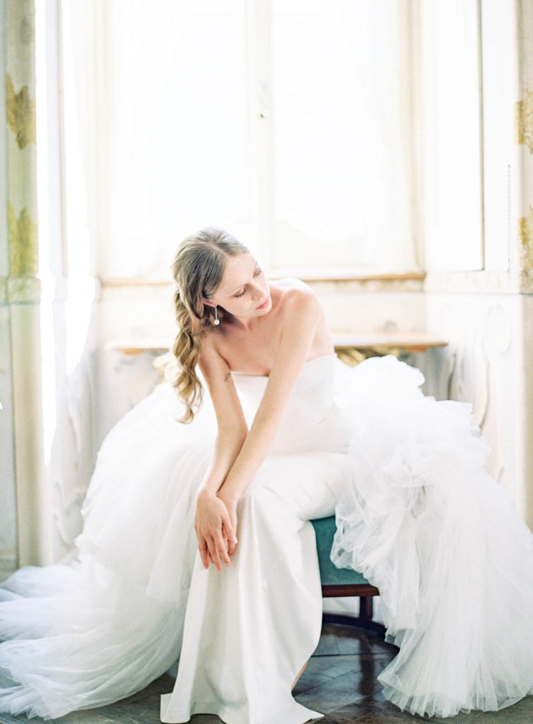 Villa Sola Cabiati Luxury wedding. Photographed by Italy wedding photographer, Amy Mulder Photography. Bride on stairs inside the villa. Bride inside of villa sitting on a chair waiting for her groom, with her overlap skirt overflowing off the chair and surrounding her. 