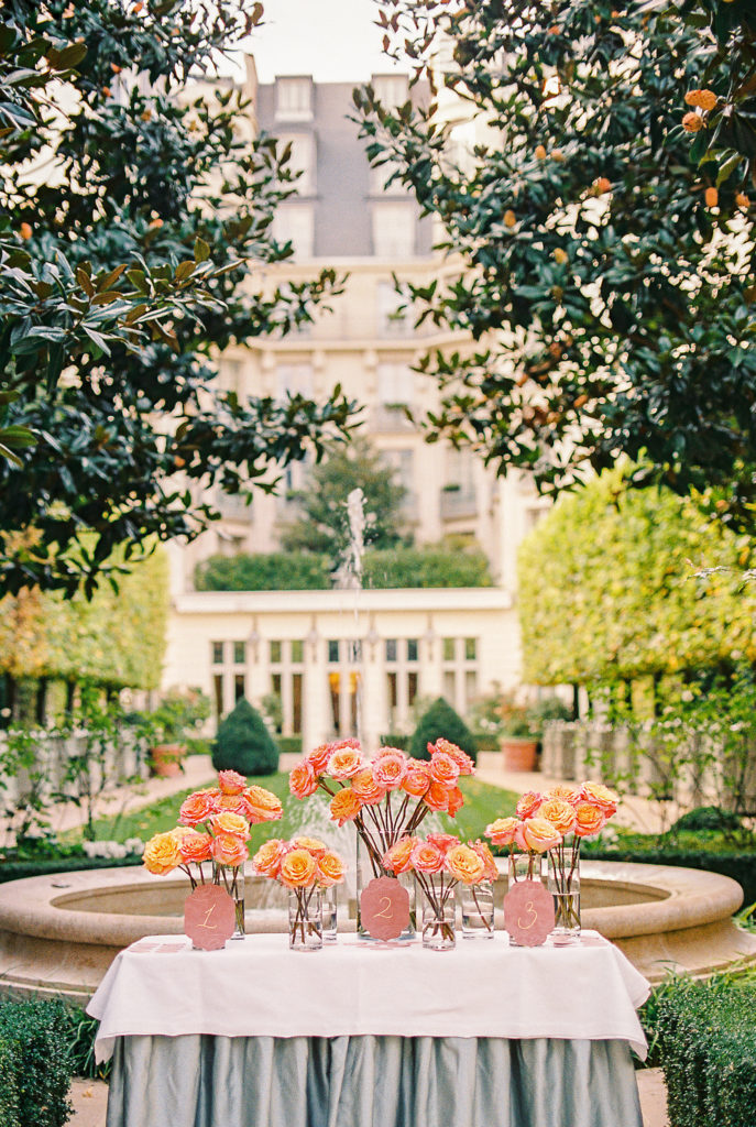 Wedding Reception at Ritz Paris with bright and bold peach and coral florals for guests seating chart.