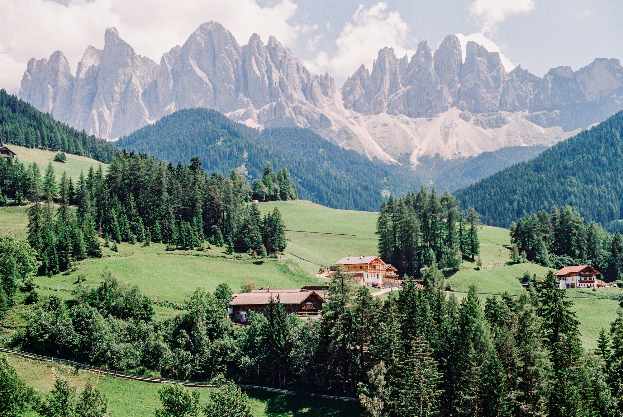 Layers of green hills and jagged stone mountains of the Dolomites in northern Italy.