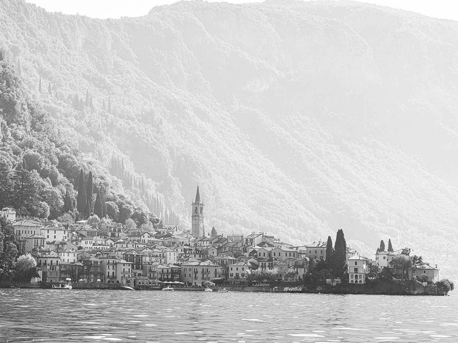 The town of Varenna with the mountains behind photographed from the middle of Lake Como in Italy