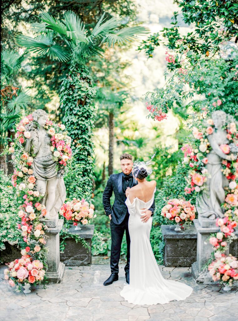 Floral installation surrounding statues with bride and groom in the middle for a Lake Como wedding in Italy photographed on film by Lake Como wedding photographer