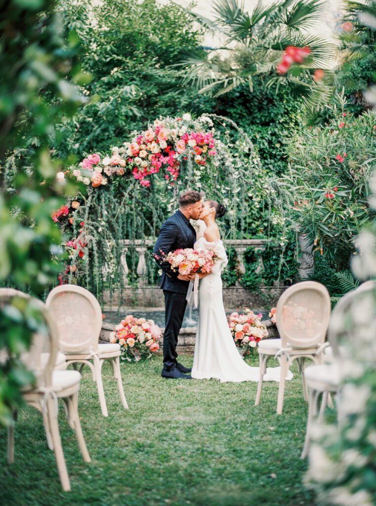 Intimate garden wedding with Vibrant colorful floral installation sweeping over the bride and groom for their Lake Como wedding in Italy photographed on film by Lake Como wedding photographer