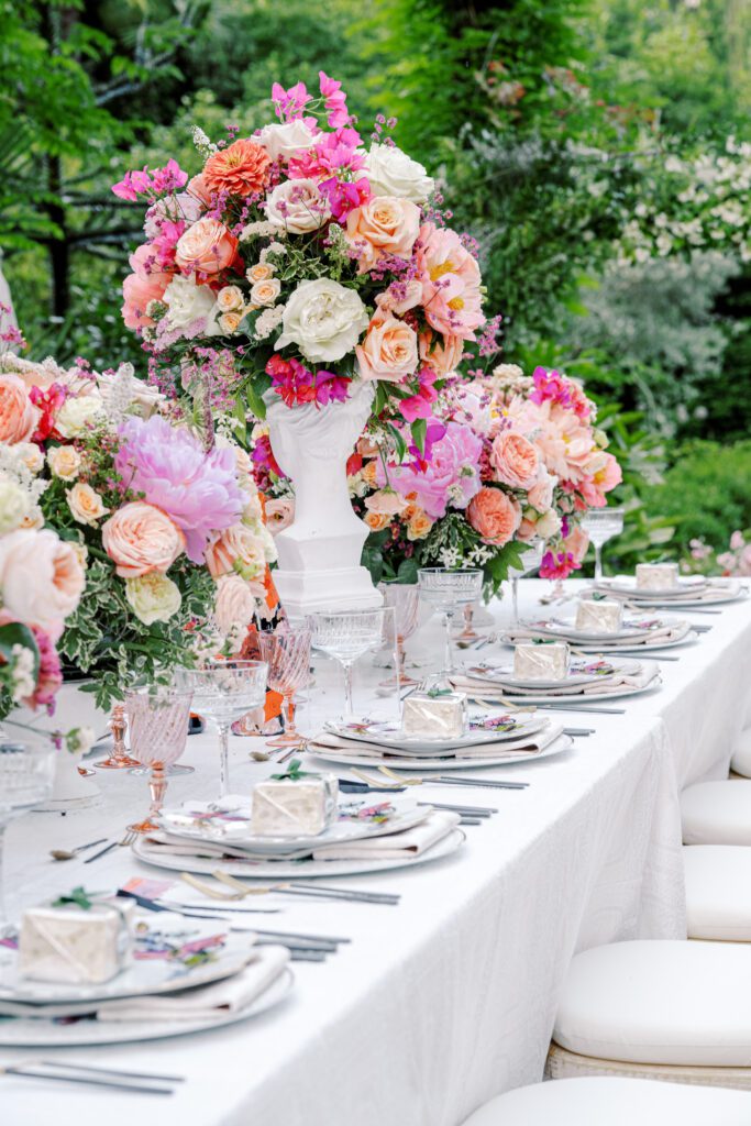 Colorful and vibrant pink and coral flowers in busts as centerpieces among patterned table settings with pink glasses for a Lake Como wedding in Italy photographed on film by Lake Como wedding photographer