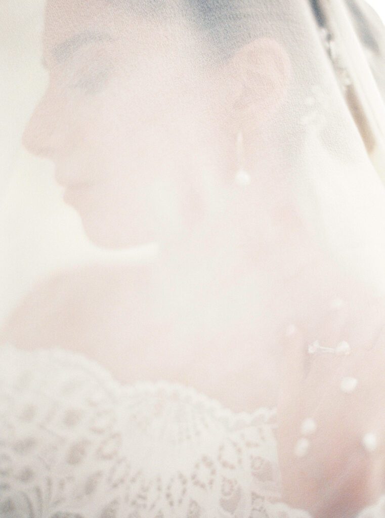 Bride in off the shoulder lace gown under her veil laughing at her Tuscany Wedding in the olive grove at Villa Montanare near Cortona, Italy photographed by Italy wedding photographer 