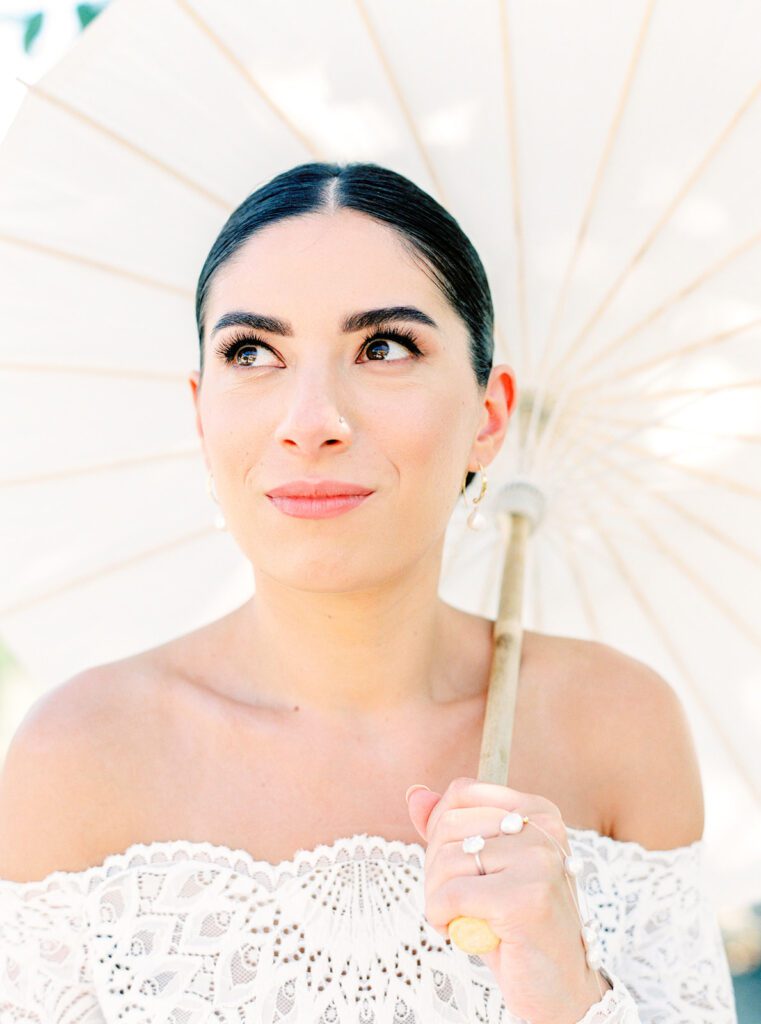Bride in off the shoulder lace gown with parasol at her Tuscany Wedding in the olive grove at Villa Montanare near Cortona, Italy photographed by Italy wedding photographer 