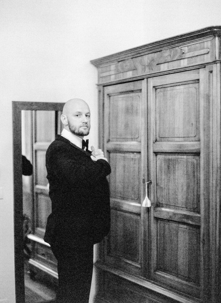 Black and white film photograph of groom getting ready for her Lake Como elopement in Italy at Villa la Cassianella photographed by Lake Como photographer