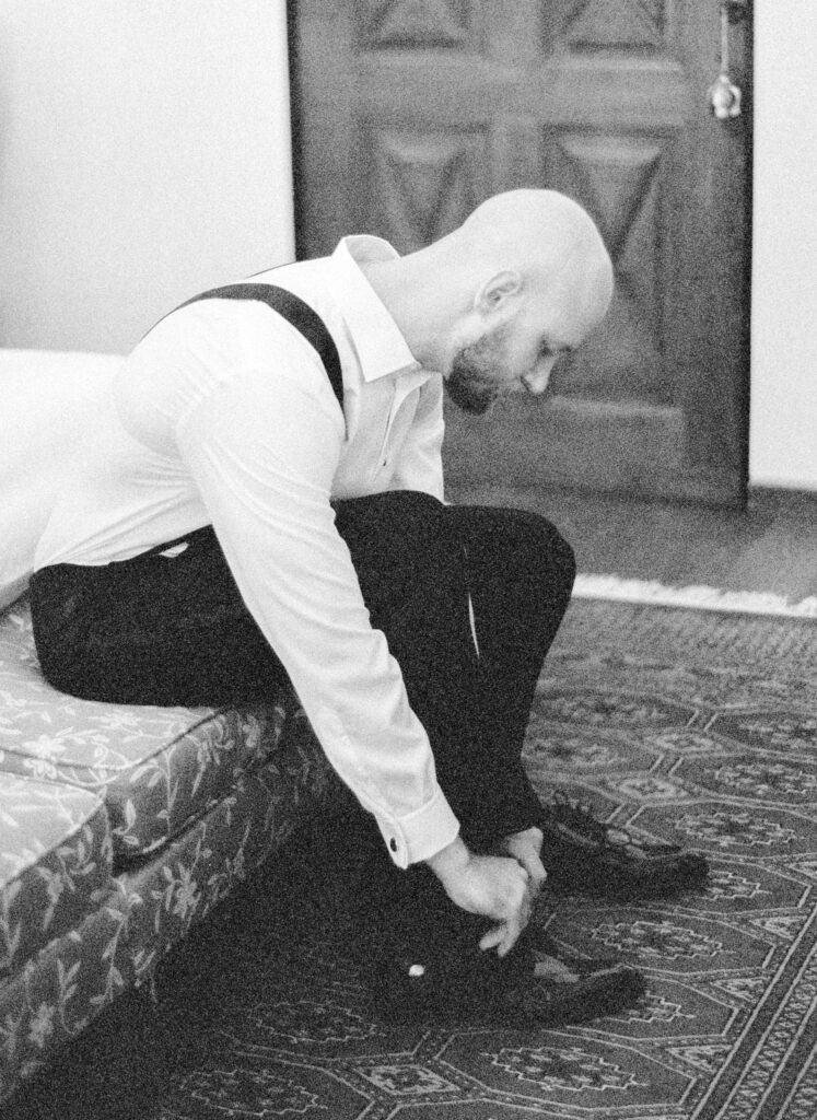 Black and white film photograph of groom getting ready for her Lake Como elopement in Italy at Villa la Cassianella photographed by Lake Como photographer