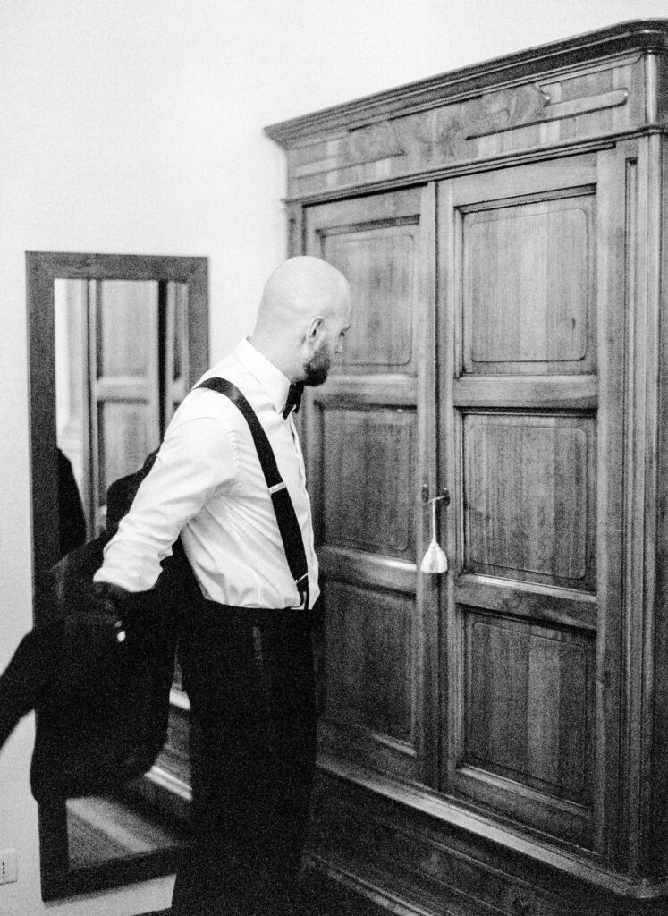 Black and white film photograph of groom getting ready for her Lake Como elopement in Italy at Villa la Cassianella photographed by Lake Como photographer