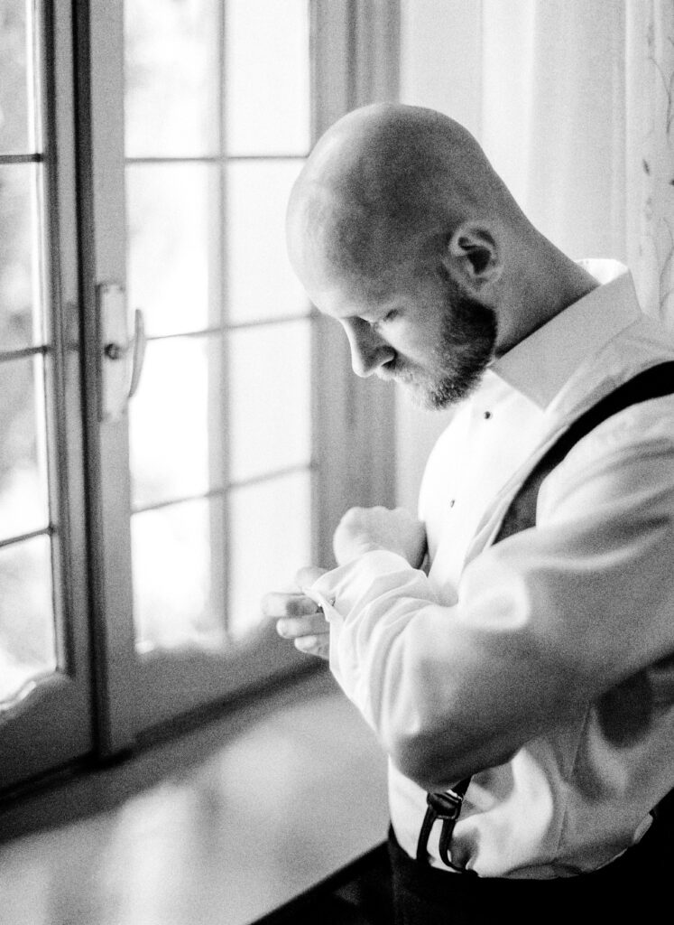 Black and white film photograph of groom getting ready for her Lake Como elopement in Italy at Villa la Cassianella photographed by Lake Como photographer