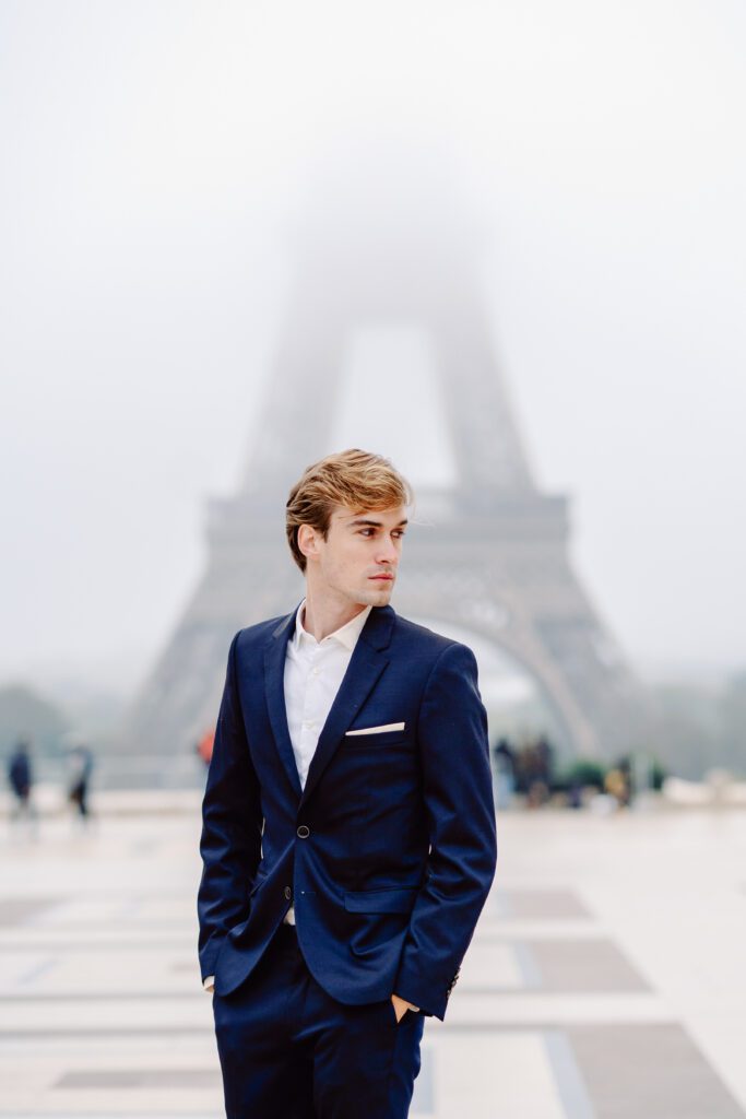 Paris pre-wedding session in front of the Eiffel Tower while it is covered in fog with bride in full train layered gown with separate off the shoulder full puffed sleeves and groom in a navy blue suit photographed by Italy destination photographer