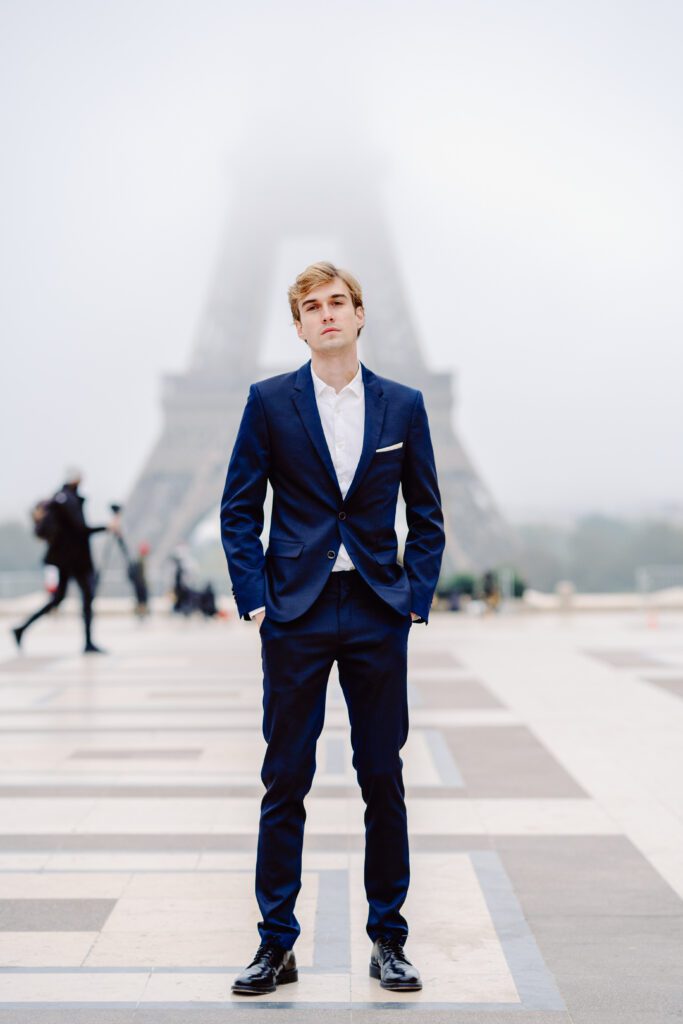 Paris pre-wedding session in front of the Eiffel Tower while it is covered in fog with bride in full train layered gown with separate off the shoulder full puffed sleeves and groom in a navy blue suit photographed by Italy destination photographer