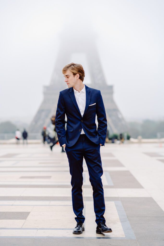 Paris pre-wedding session in front of the Eiffel Tower while it is covered in fog with bride in full train layered gown with separate off the shoulder full puffed sleeves and groom in a navy blue suit photographed by Italy destination photographer