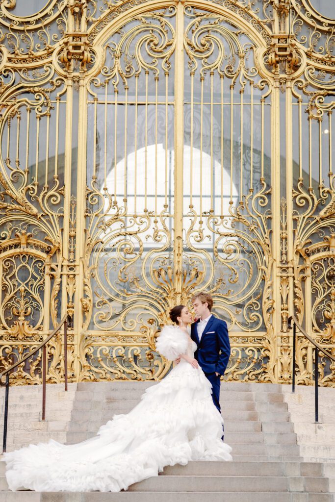 Paris pre-wedding session in front of Petite Palais with bride in full train layered gown with separate off the shoulder full puffed sleeves and groom in a navy blue suit photographed by Italy destination photographer