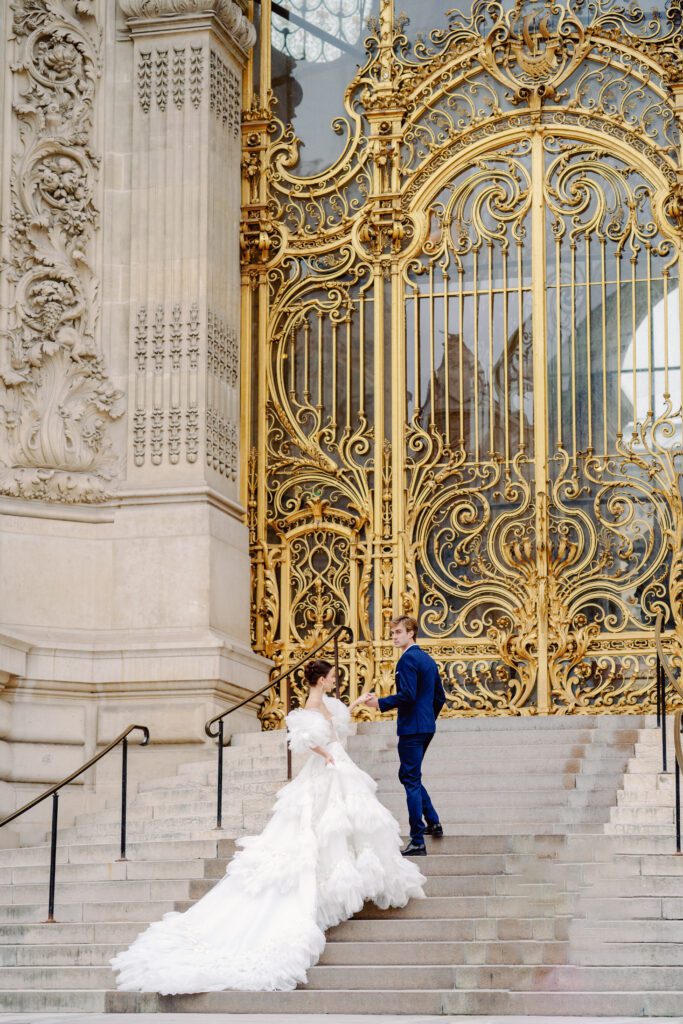 Paris pre-wedding session in front of Petite Palais with bride in full train layered gown with separate off the shoulder full puffed sleeves and groom in a navy blue suit photographed by Italy destination photographer