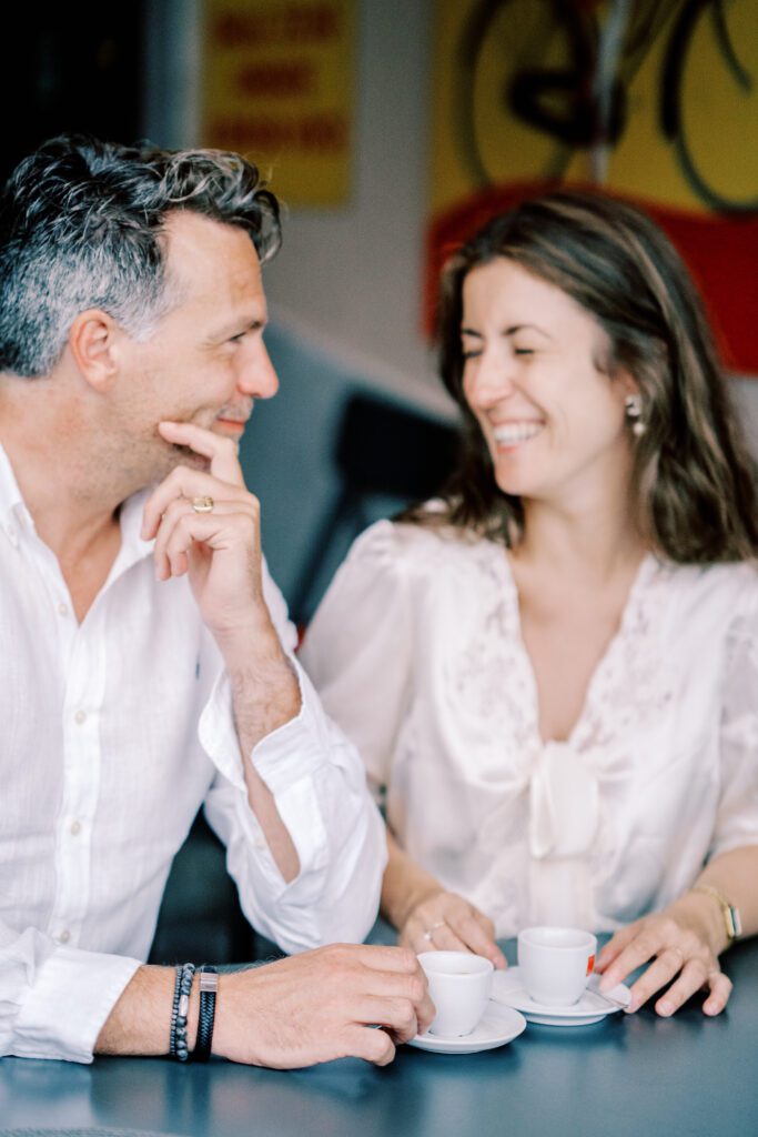 Lake Como vacation session in Argegno at cafe enjoying espresso, laughing and holding hand photographed by Lake Como photographer